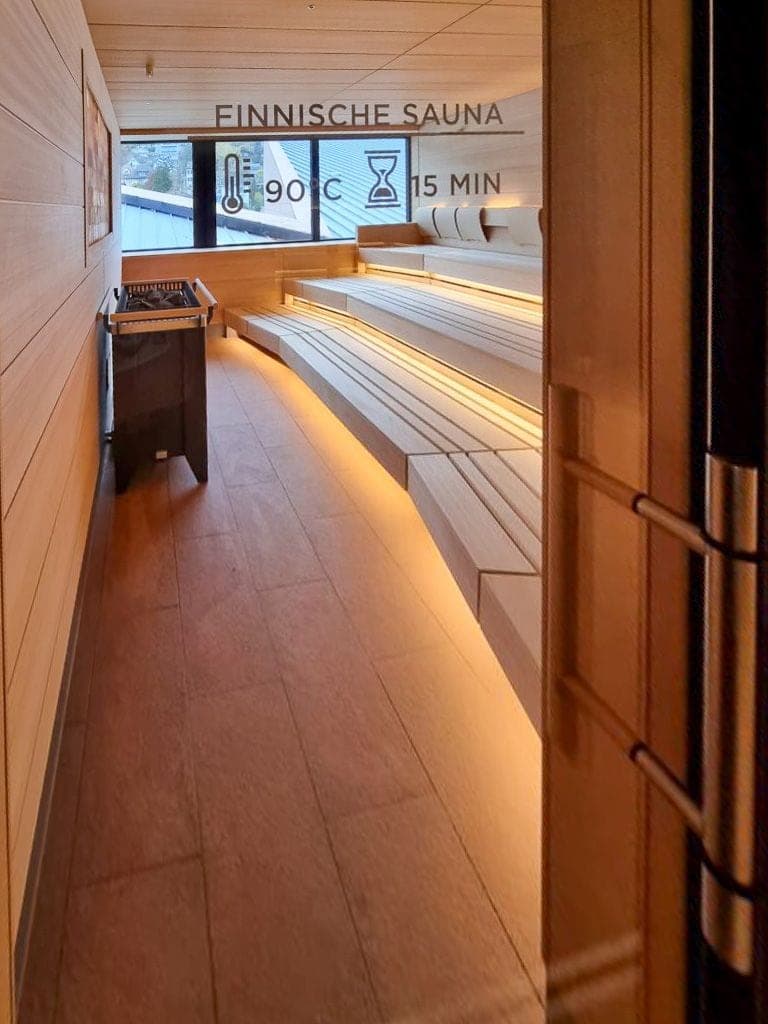 Finnische Sauna mit warmer LED-Beleuchtung und Natursteinboden